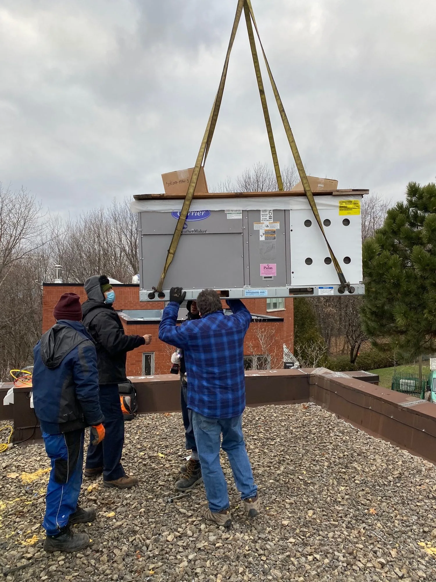 A rooftop unit lowered by crane while JCD technicians guide it into place