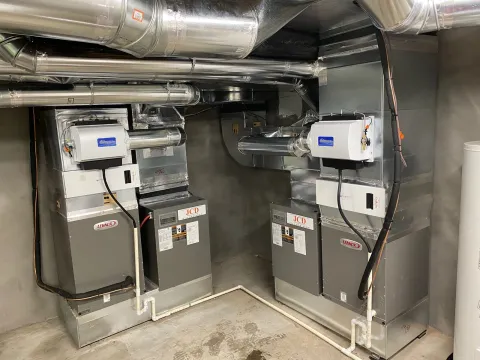 Two Lennox furnaces with humidifiers in a basement mechanical room, each with a JCD label