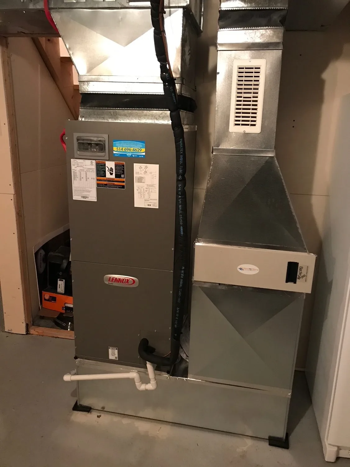 A Lennox air handler with a JCD service sticker, beside a return duct fitted with an electronic air cleaner